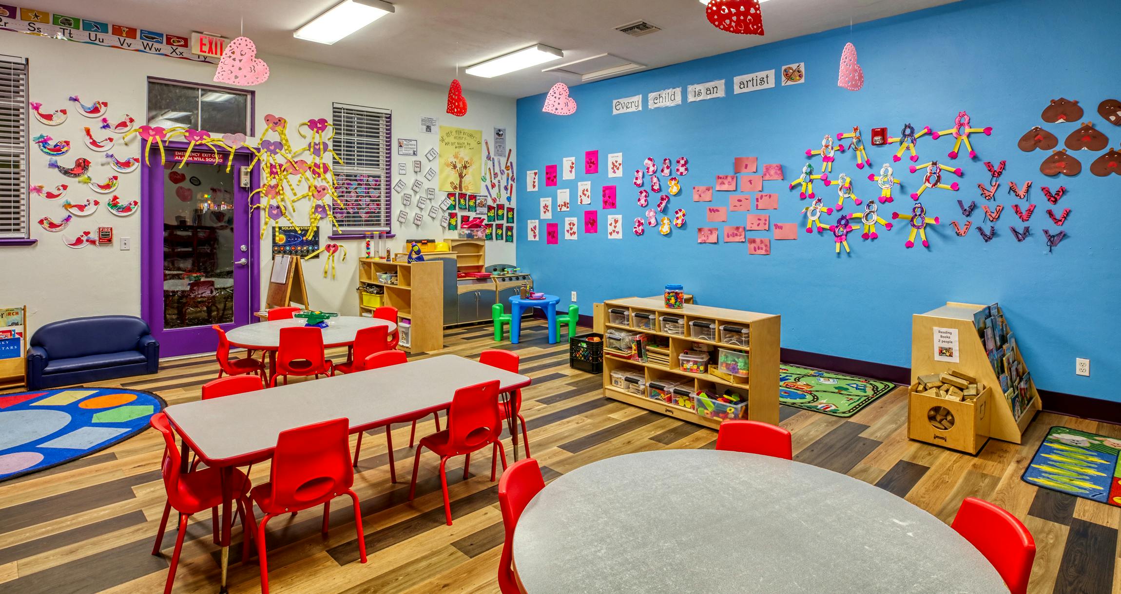 Classroom with tables and chairs, children's art on the walls