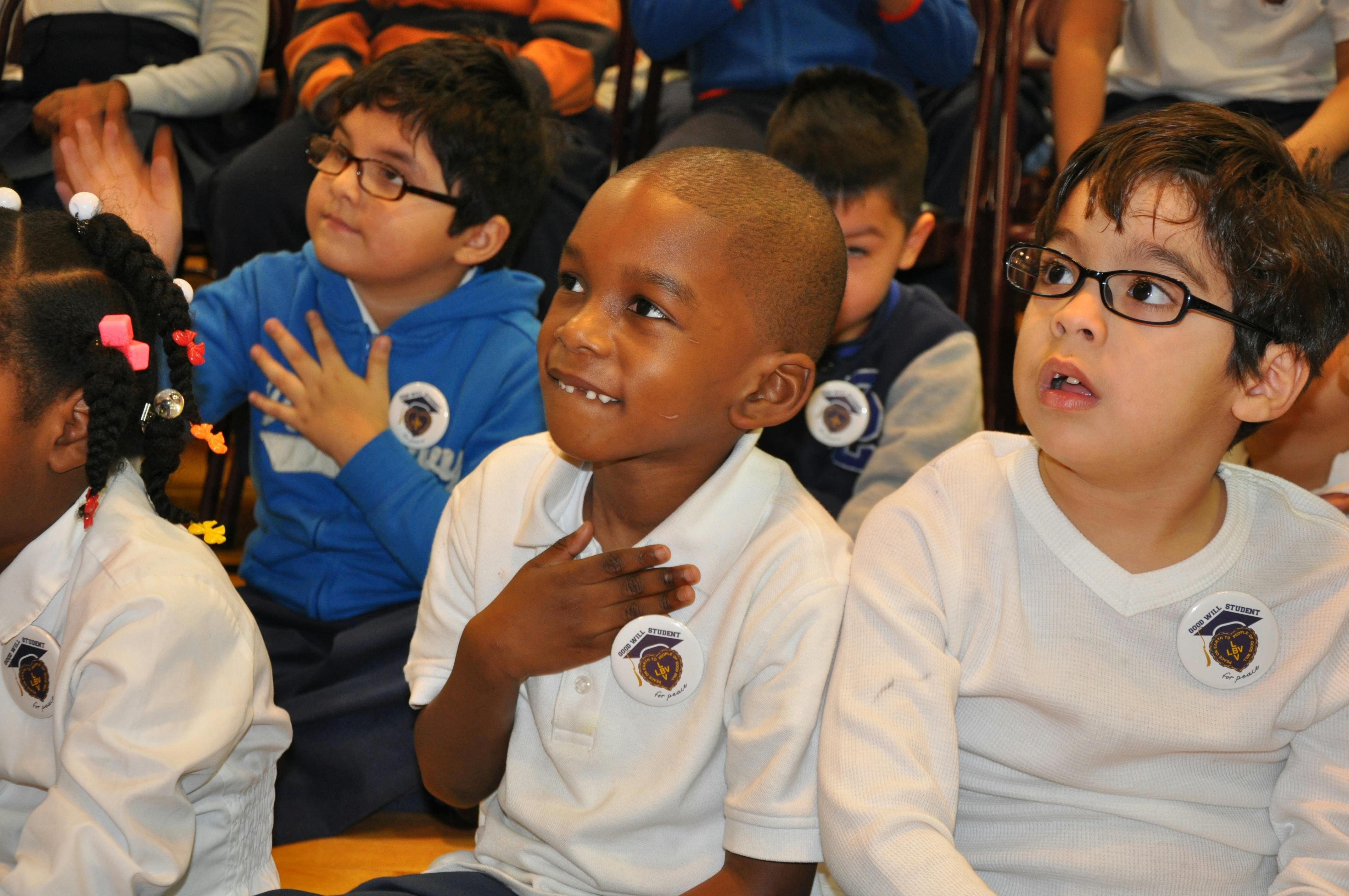 Group of children with their hands over their hearts, some wearing glasses