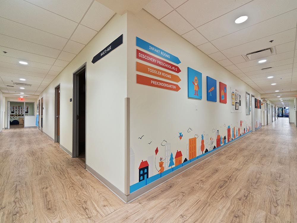 Hallway in a childcare facility with directional signs and colorful wall decals