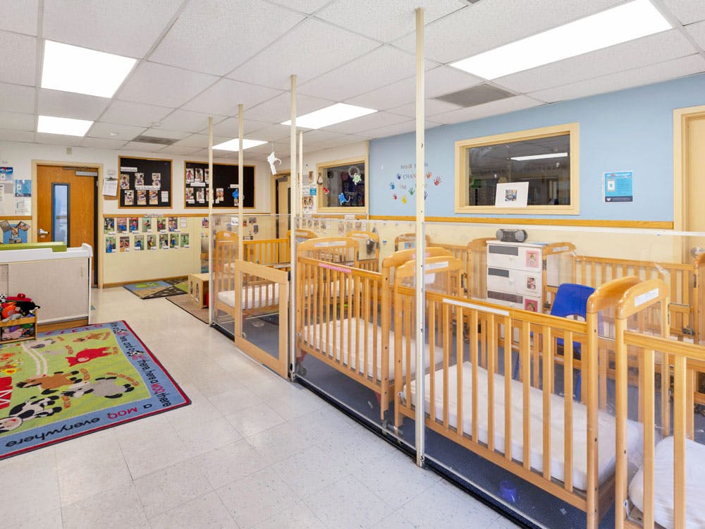 Cribs inside a daycare room, separated by clear dividers