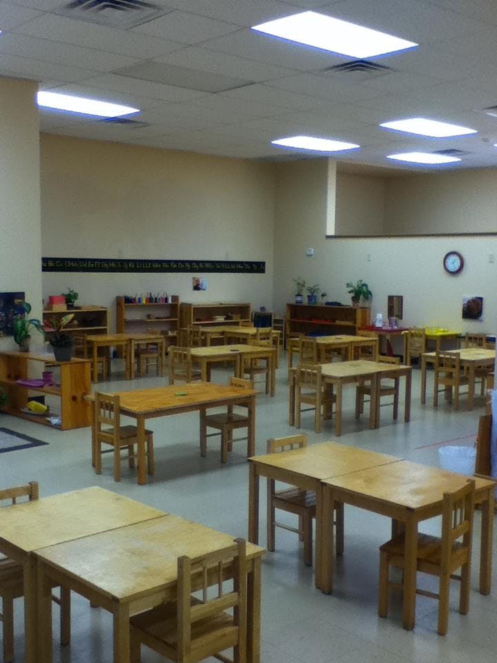 Empty classroom with small wooden tables and chairs