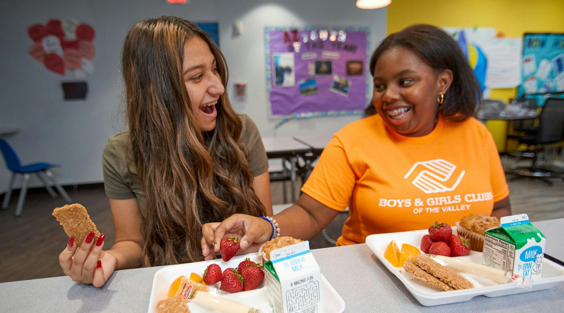 Two people smiling while eating lunch from trays