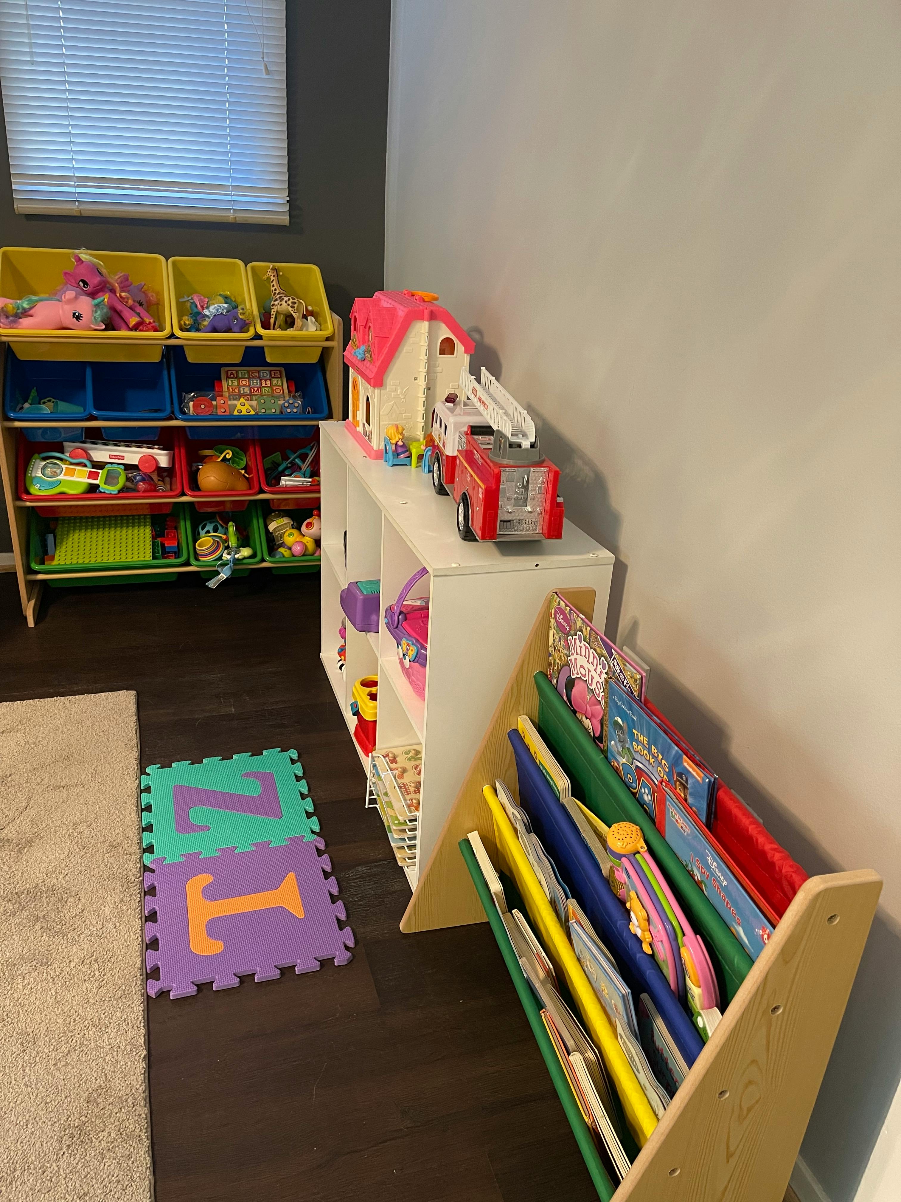 Children's room with toy storage, playhouse, fire truck, and book display