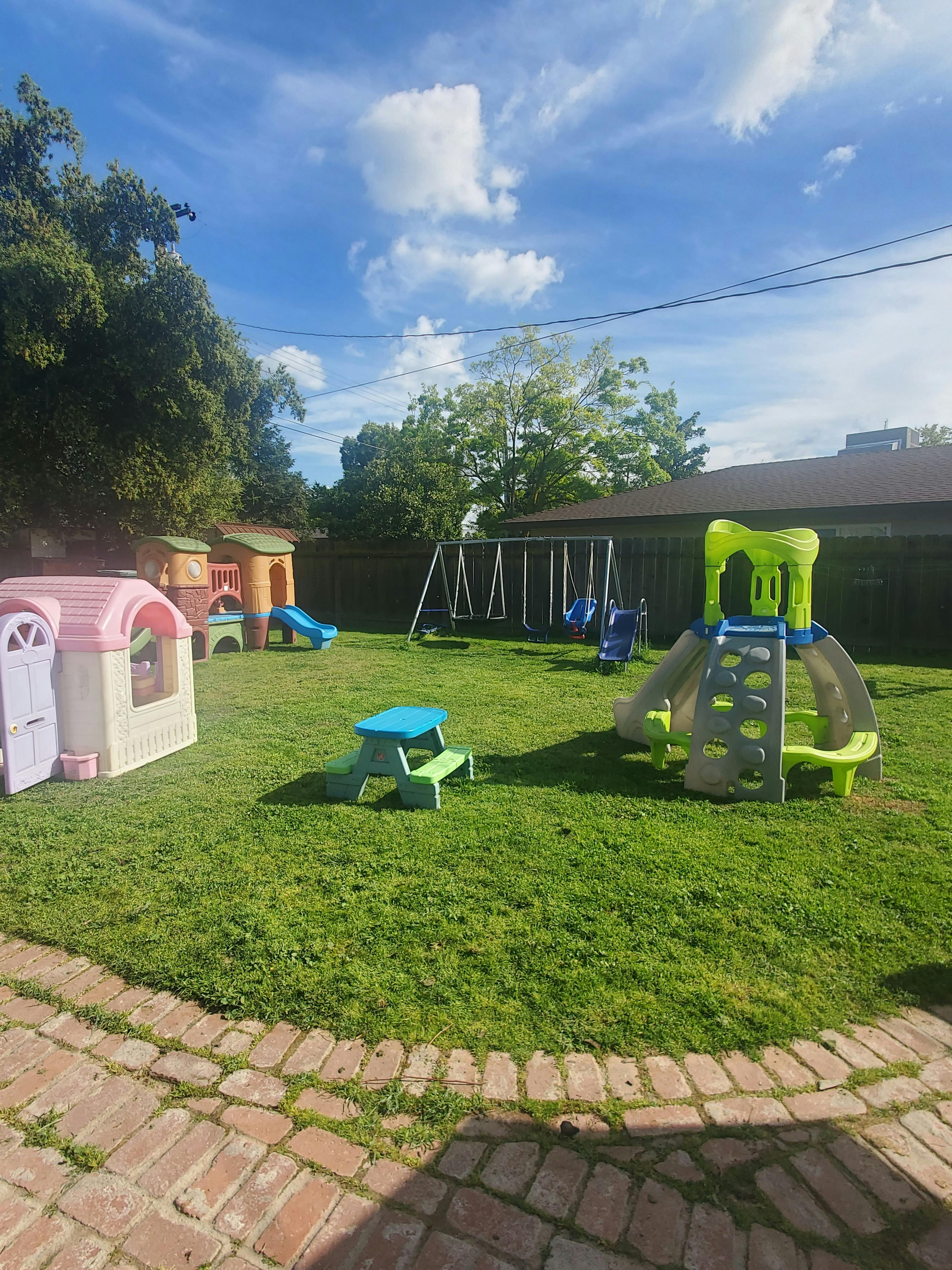 Backyard playground with swings, slides, and playhouses on green grass