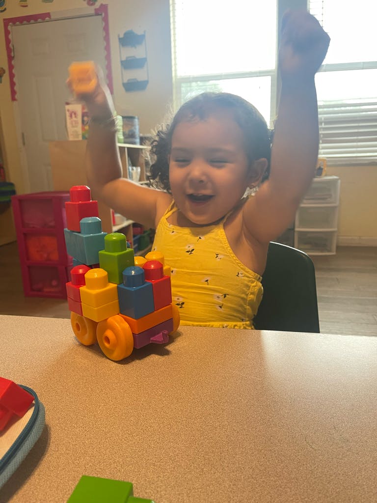 Child playing with a colorful toy train, arms raised