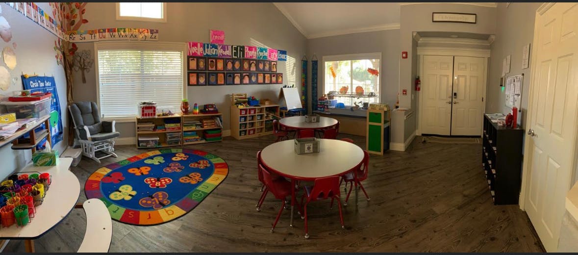 Classroom with tables, chairs, and a colorful rug