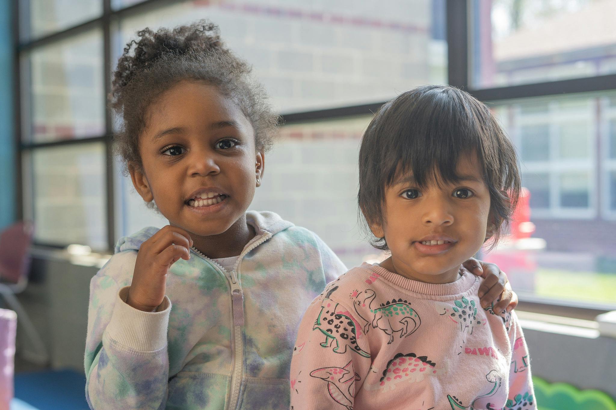 Two children standing together, one with an arm around the other