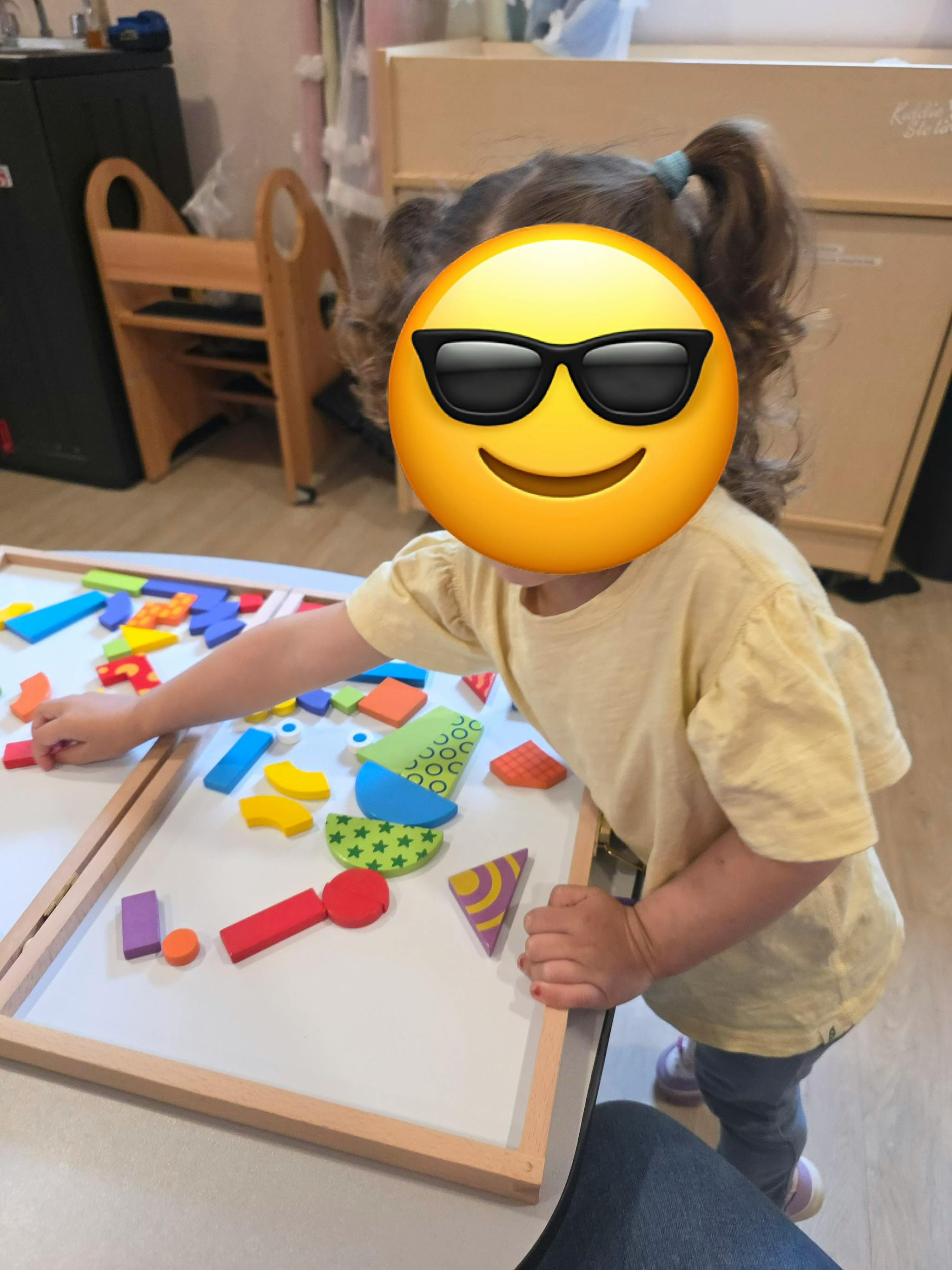 Child playing with colorful wooden shapes on a white board