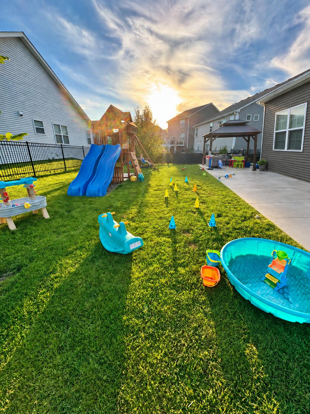 Backyard playground with toys and play structures at sunset