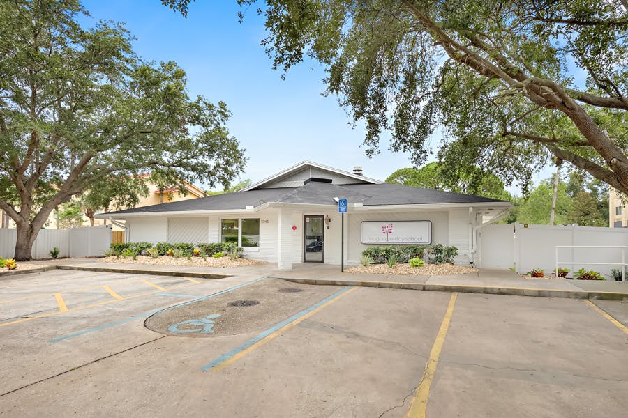 White building with a black roof and a parking lot in front