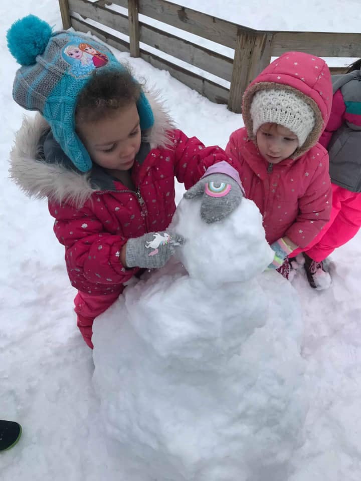 Two children building a snowman in the snow