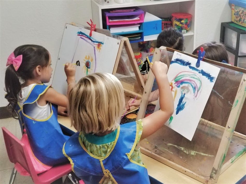Children painting at easels in a classroom