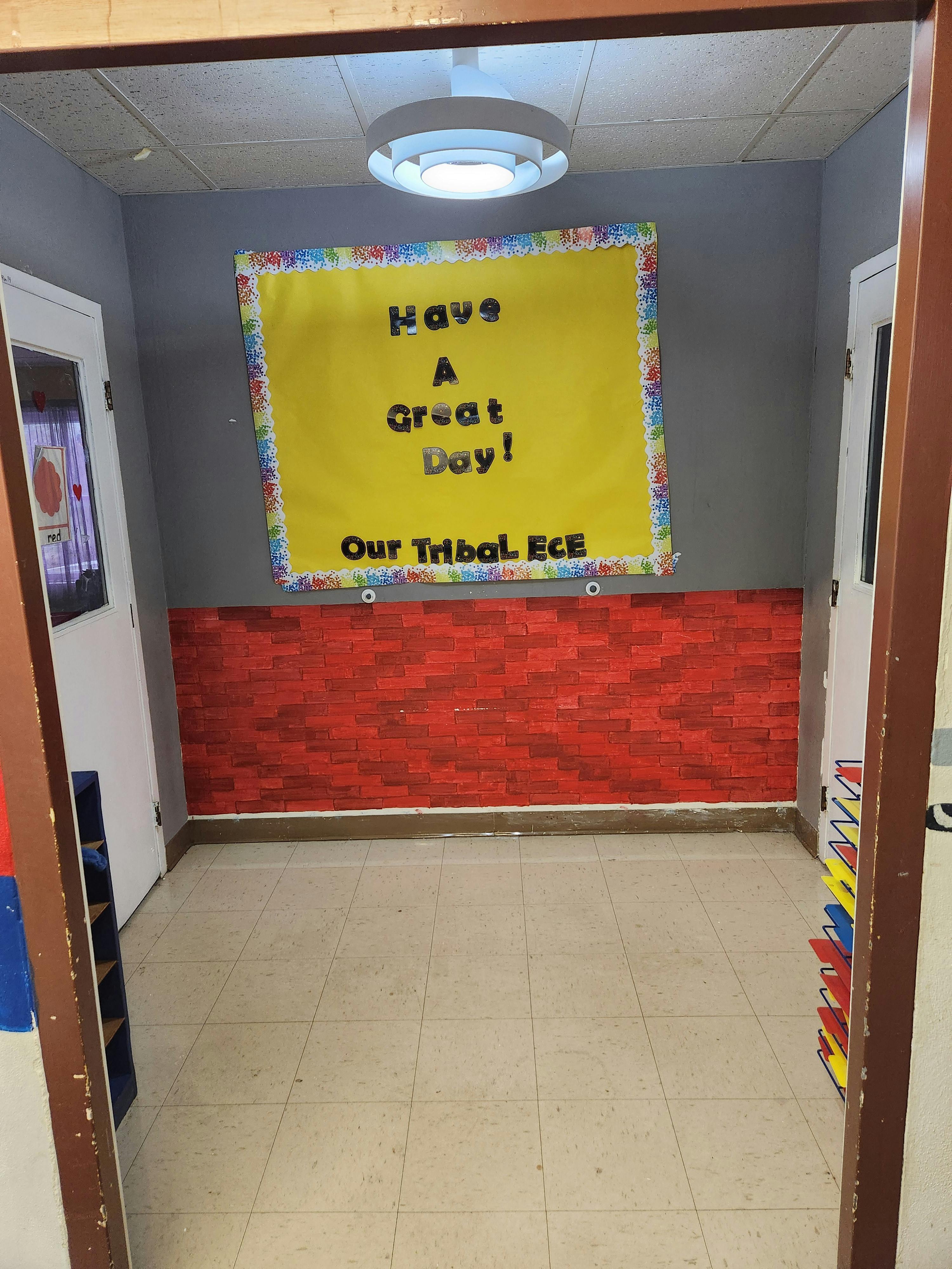Hallway with a yellow bulletin board that reads "Have A Great Day! Our Tribal ECE"