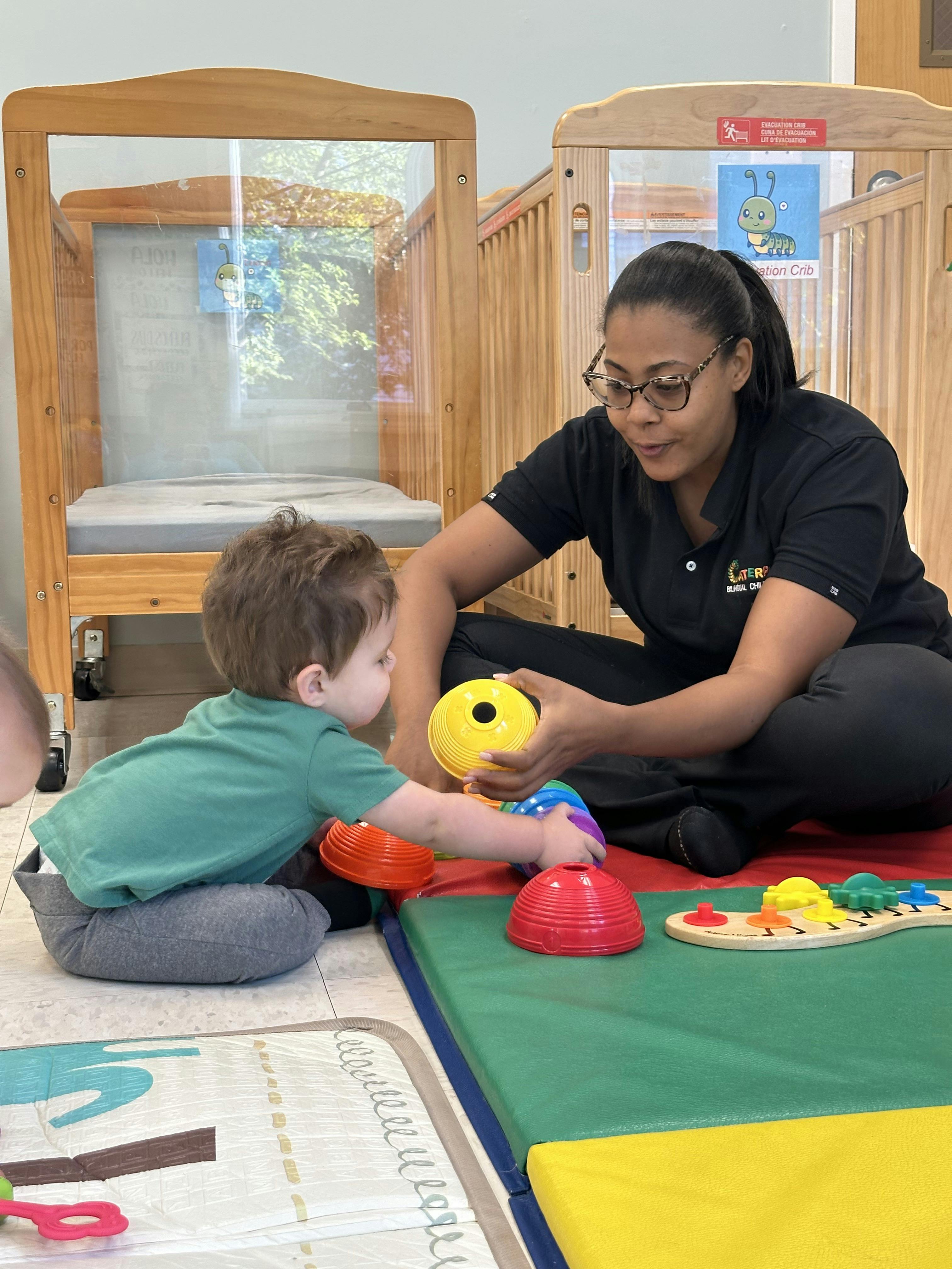 Adult and child playing with stacking cups in a daycare