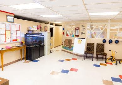 Classroom with an aquarium, chairs, and a small tricycle