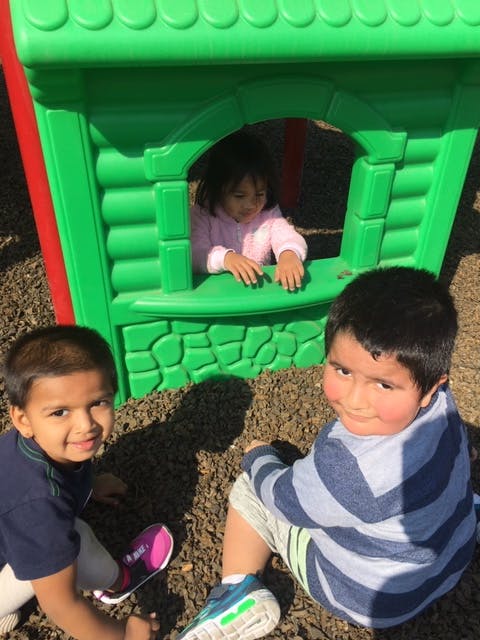 Three children playing on a playground structure