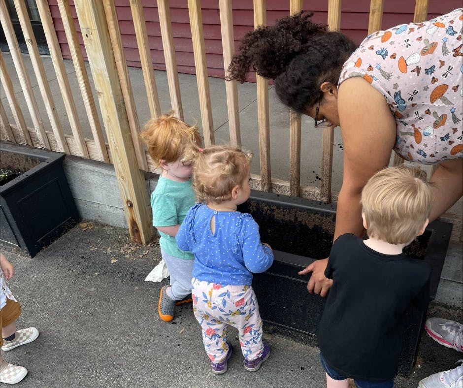 Person and three children looking into a planter