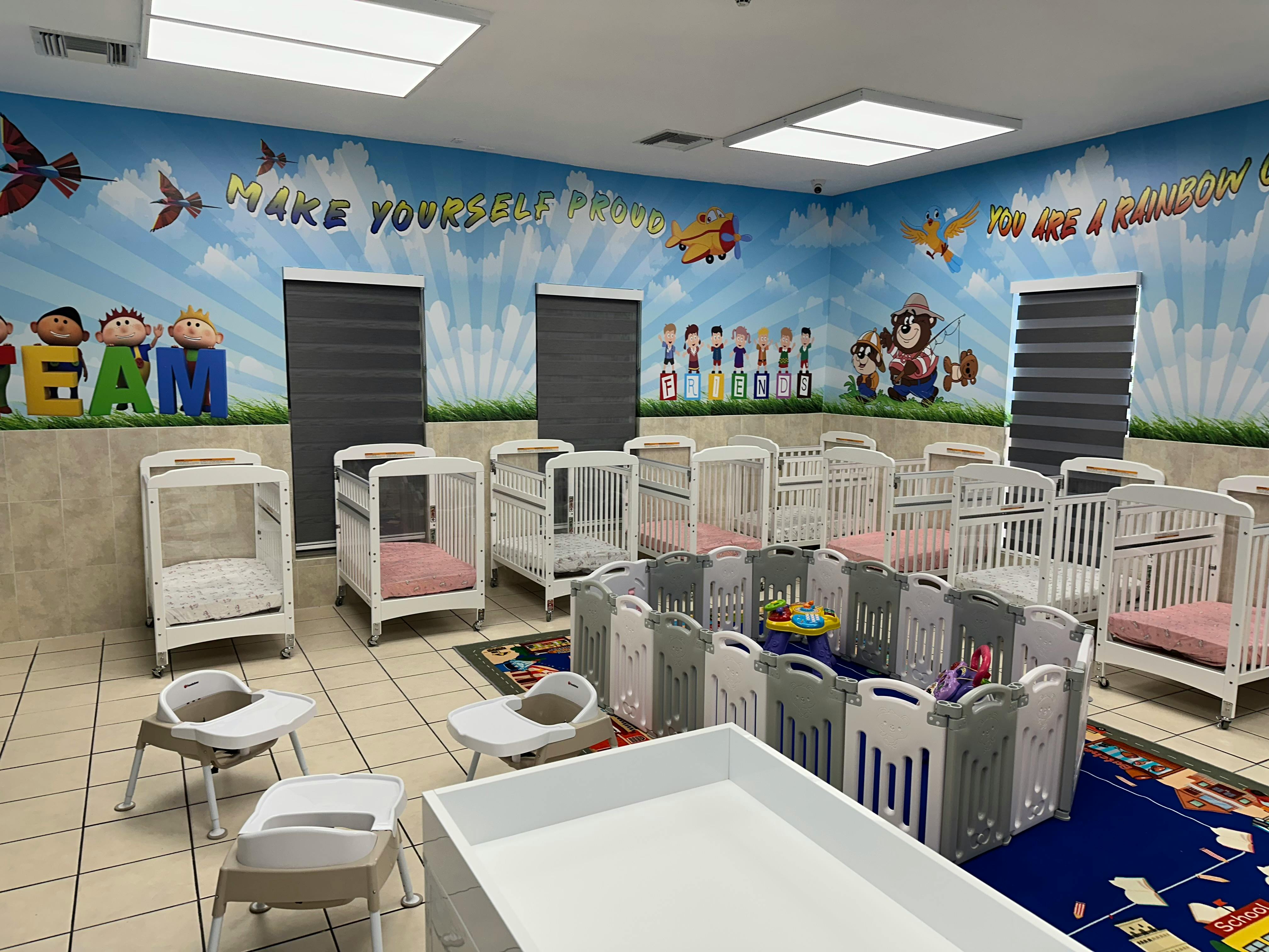 Room with multiple cribs and playpens, mural on the wall
