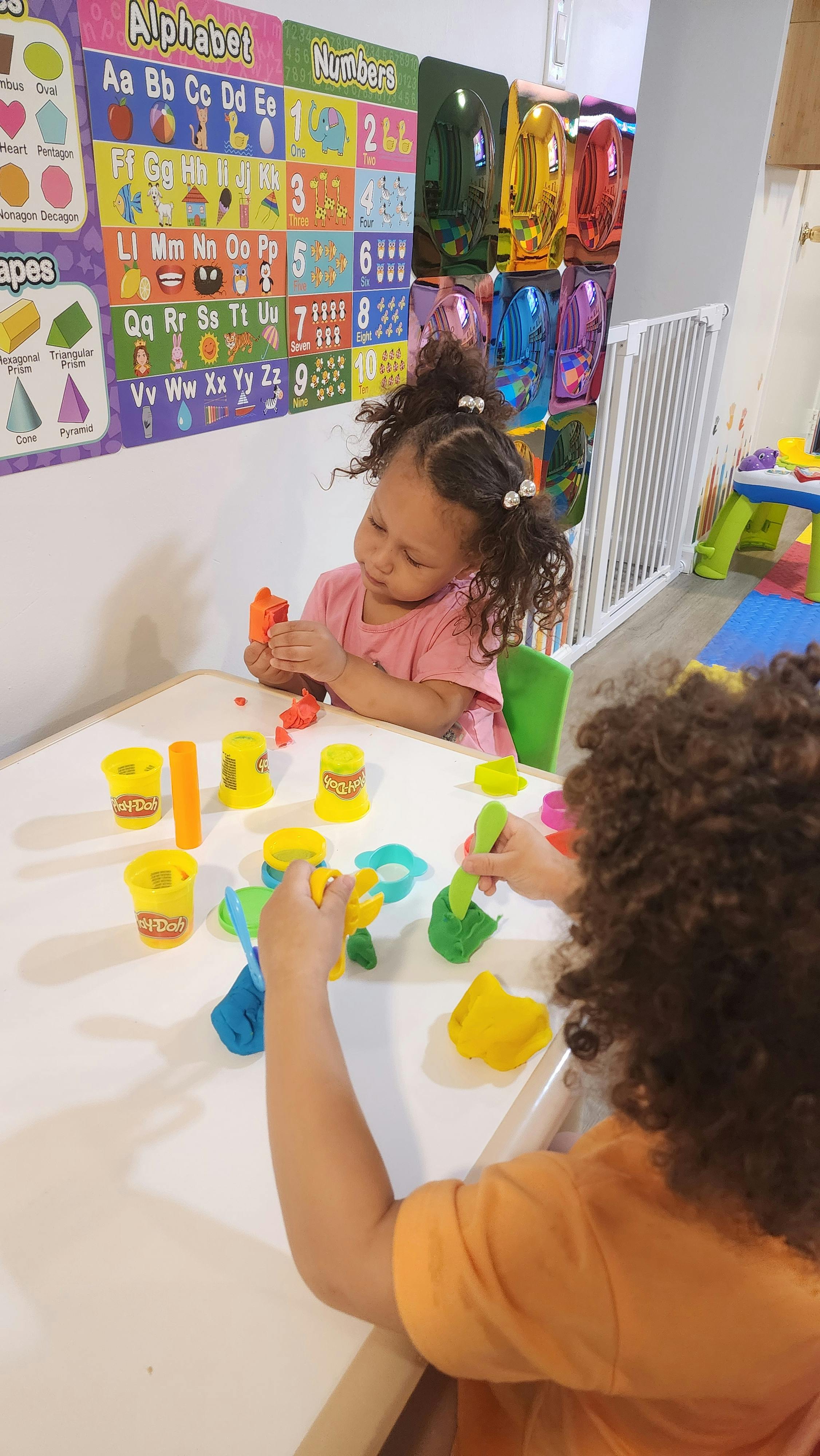 Two children playing with modeling clay at a small table