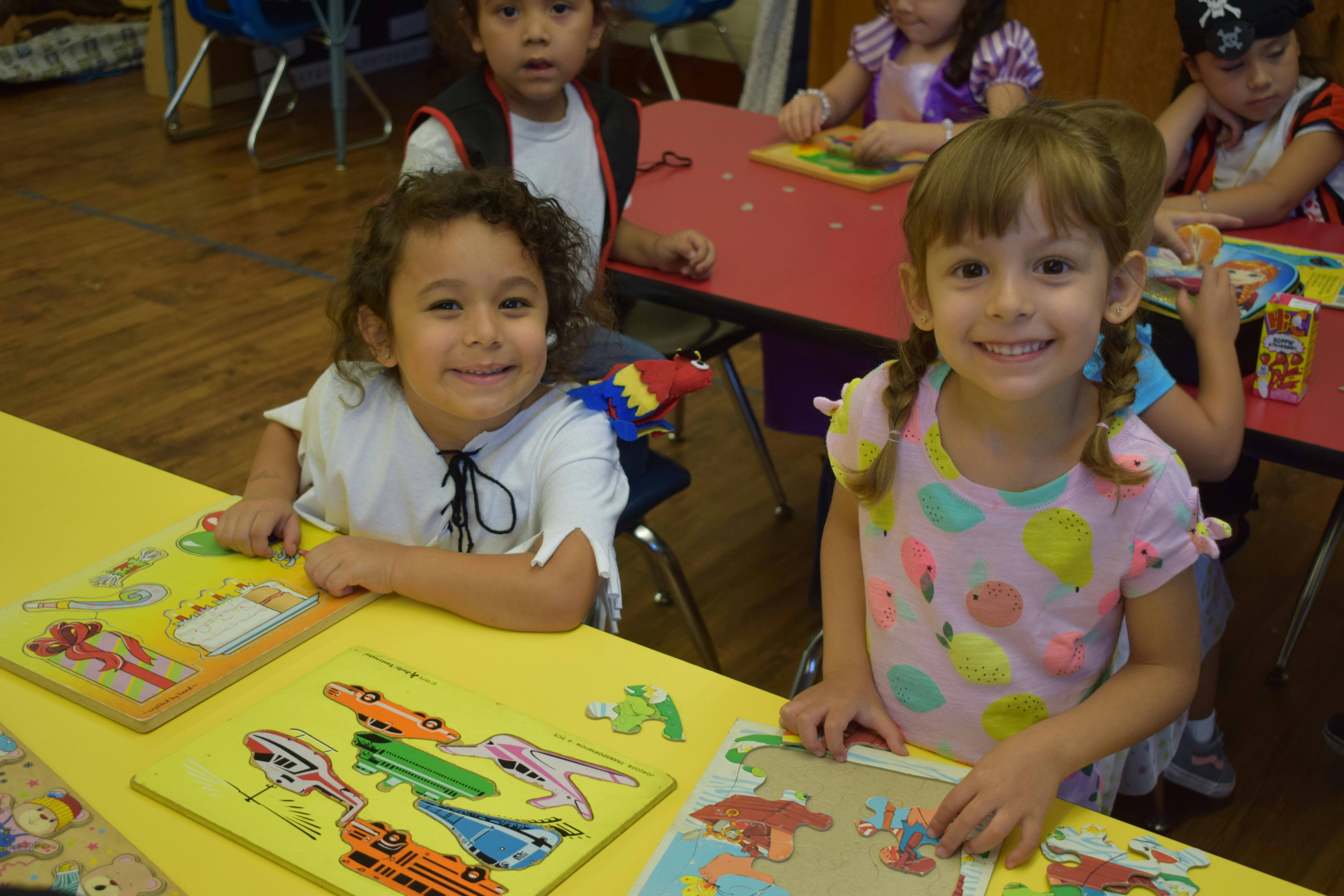 Two children at a table with puzzles in-progress puzzles