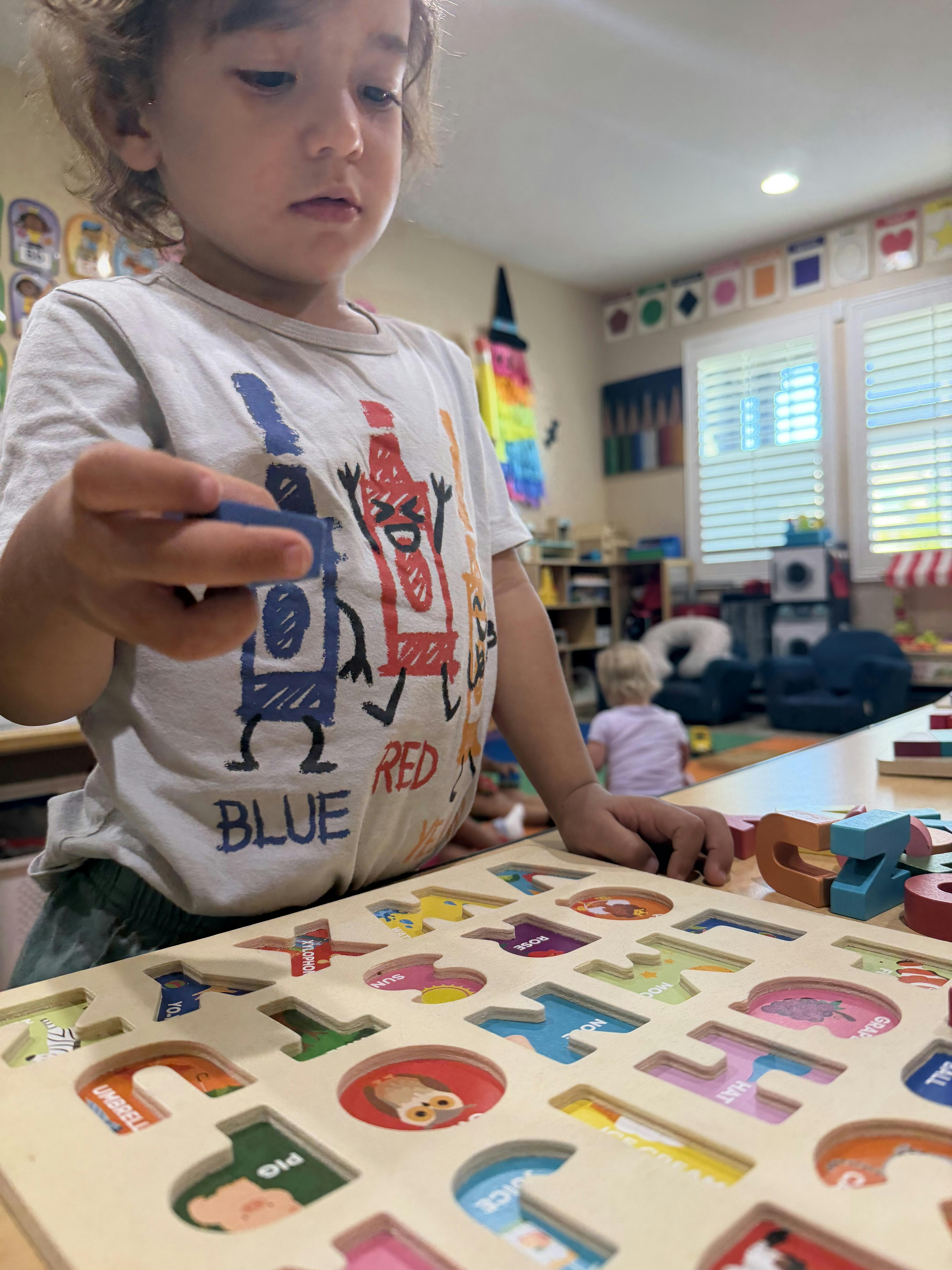 Child playing with an alphabet puzzle in a classroom