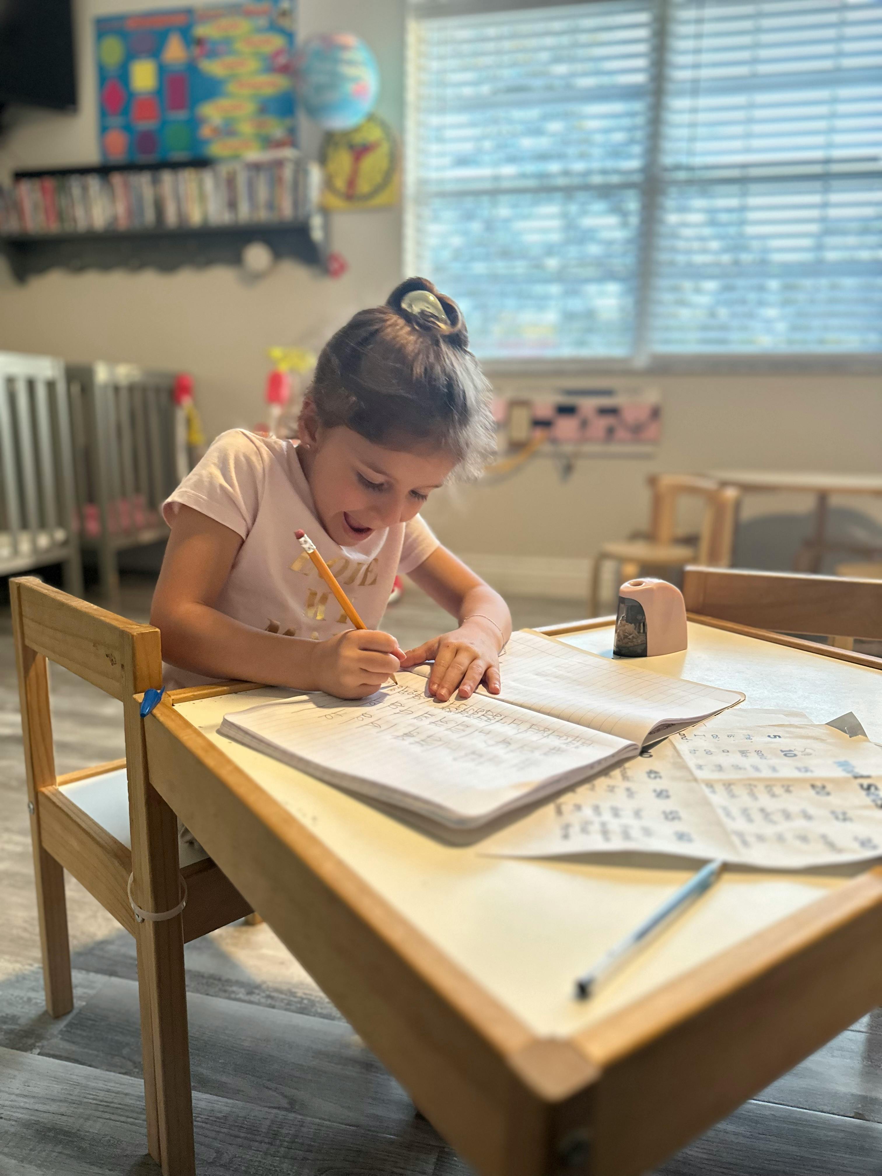 Child writing in a notebook at a table