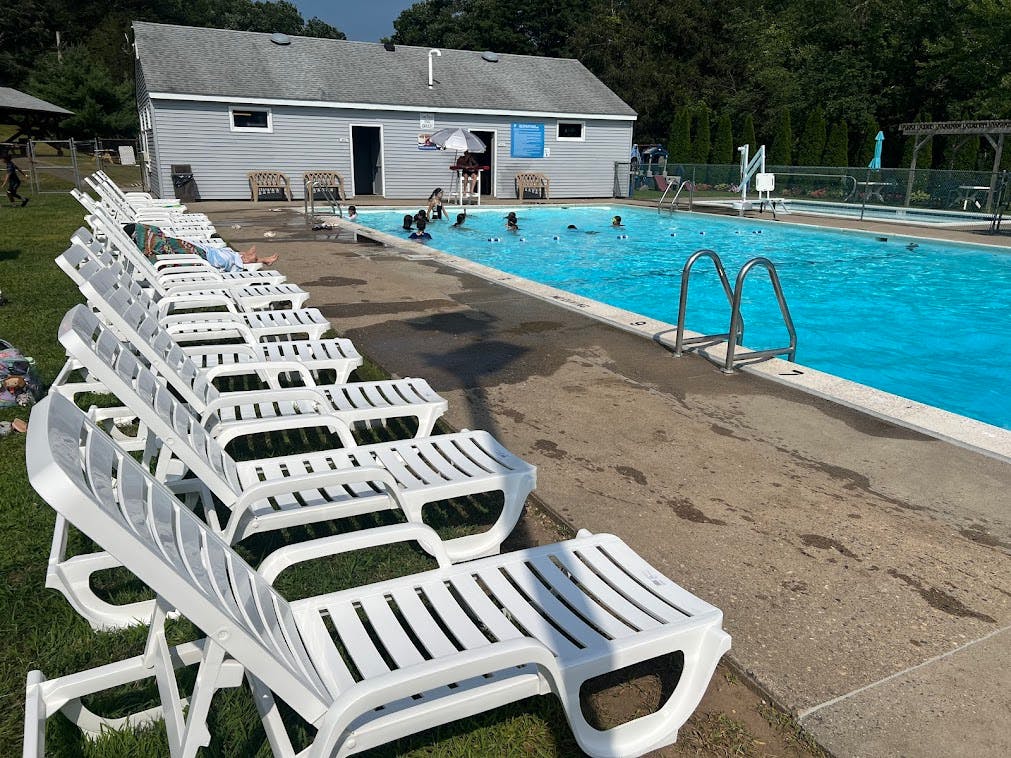 People swimming in a pool with lounge chairs lining the side