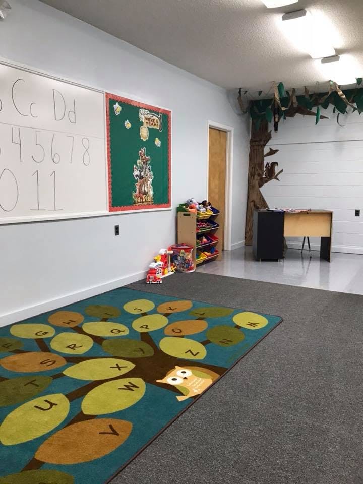 Classroom with a whiteboard, bulletin board, and a tree-themed rug