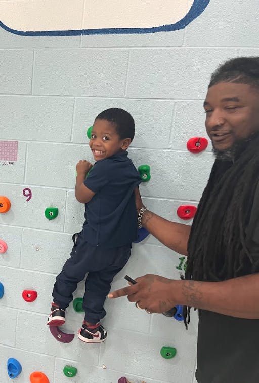 Child on a climbing wall with a person standing next to them