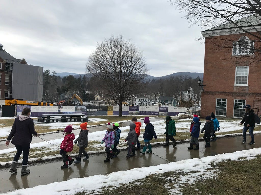 Adult and children walking on a sidewalk with snow on the ground
