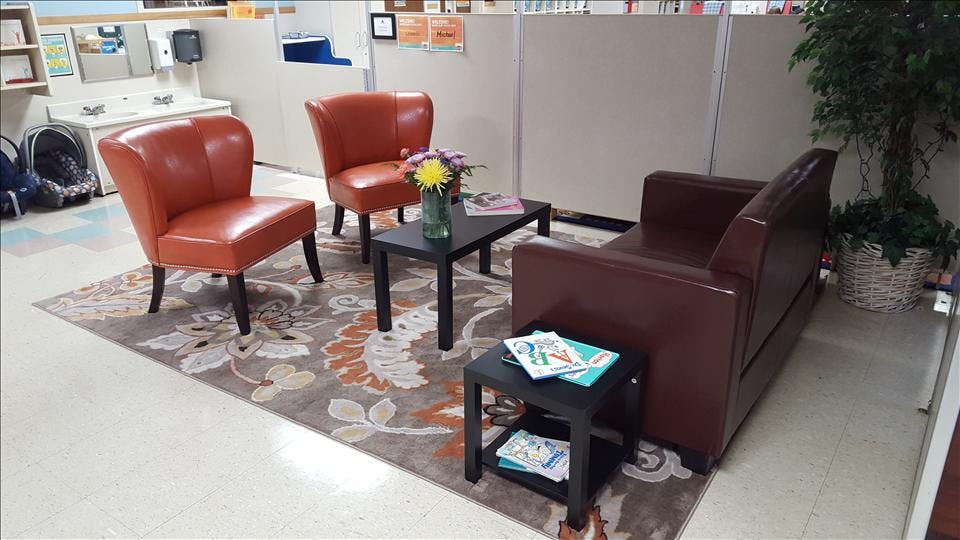 Lounge area with two orange chairs and a brown couch on a patterned rug