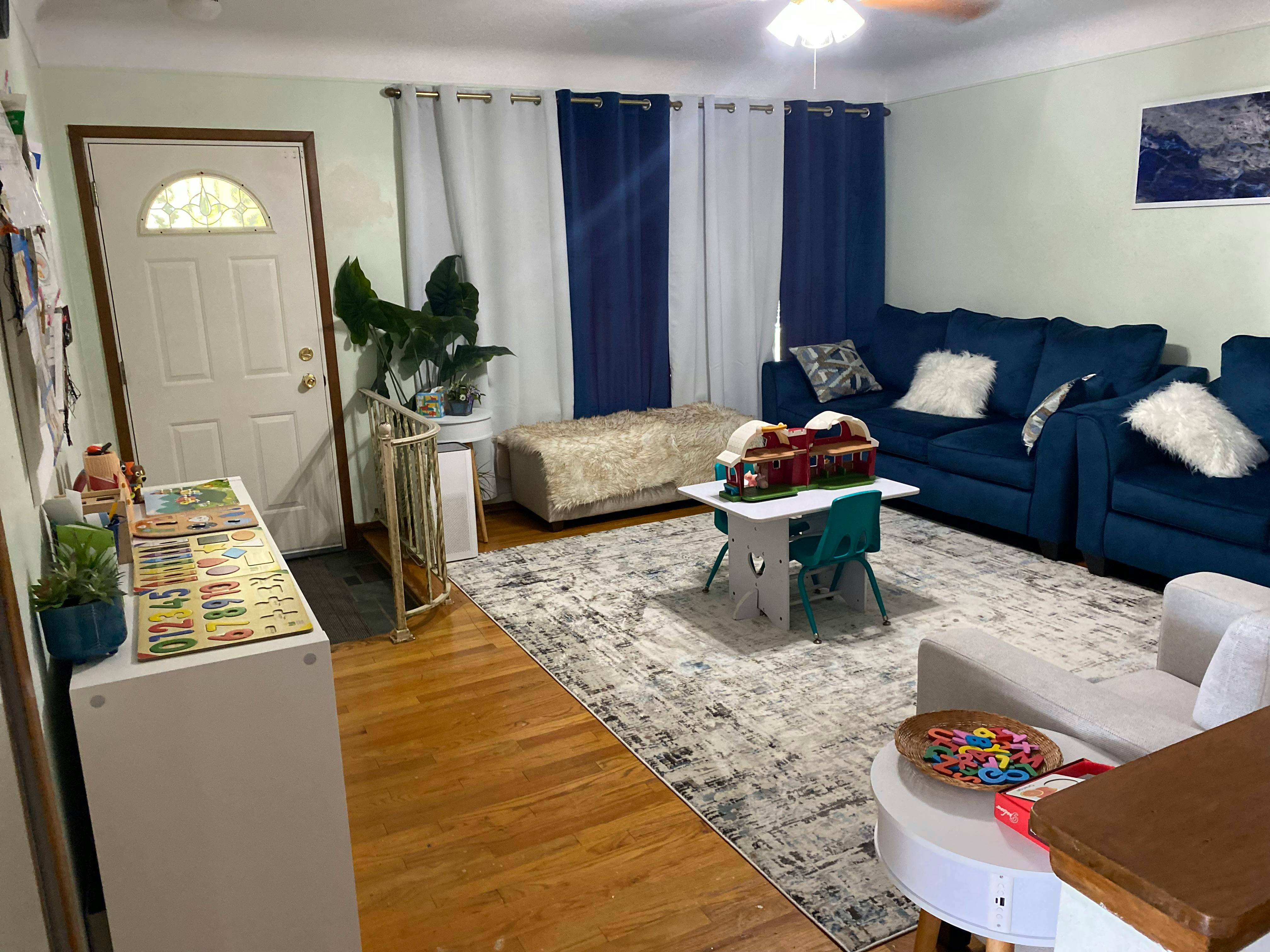 Living room with blue sofas, a patterned rug, and a white door