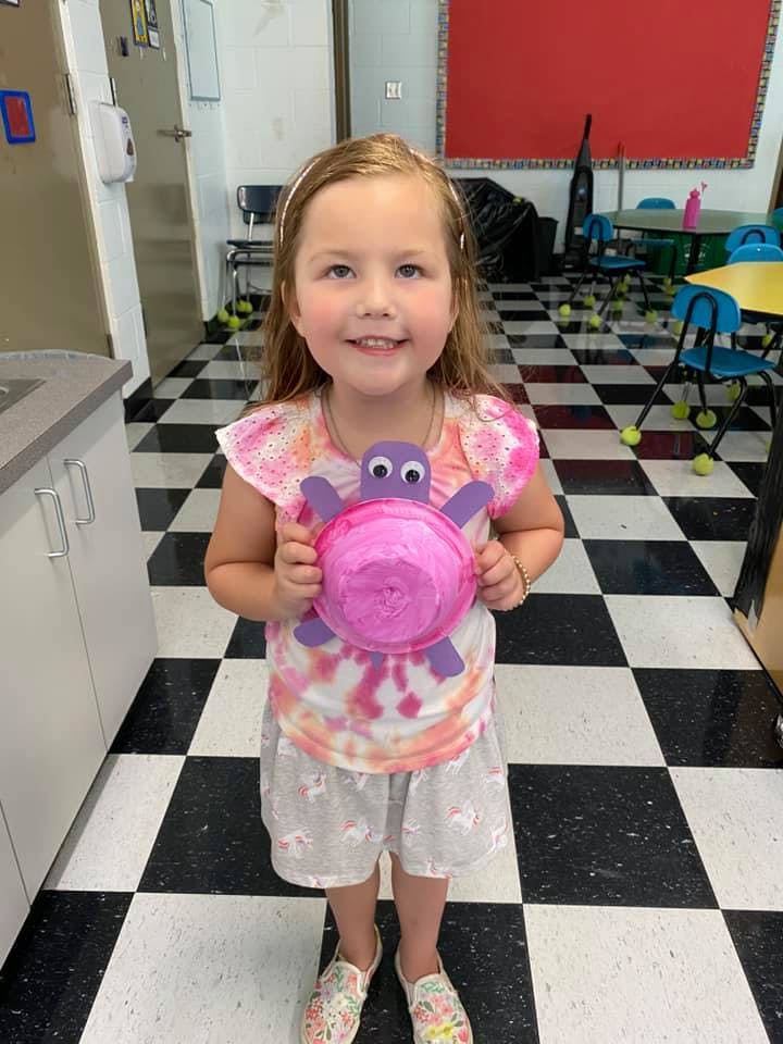 Child holding a craft turtle in a classroom
