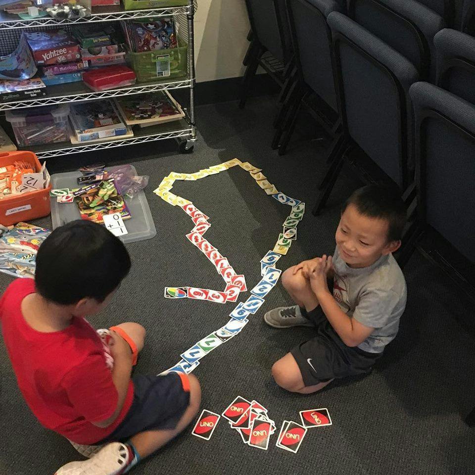 Two children sitting on the floor playing with cards