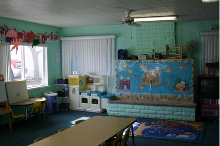 Classroom with play kitchen, tables, and a mural