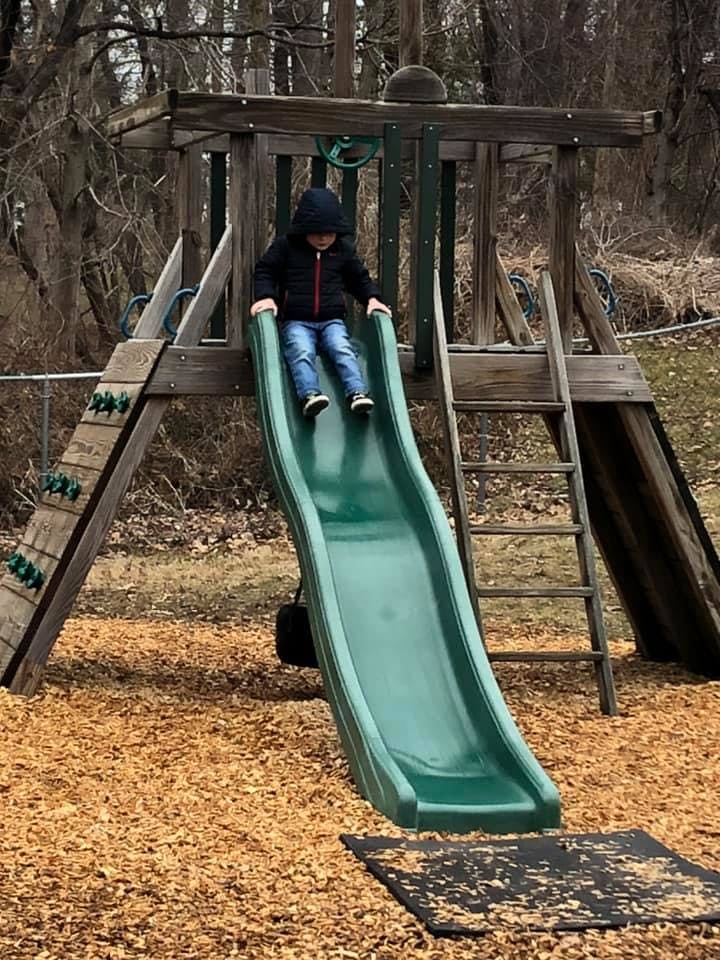 Child on a green slide at a playground