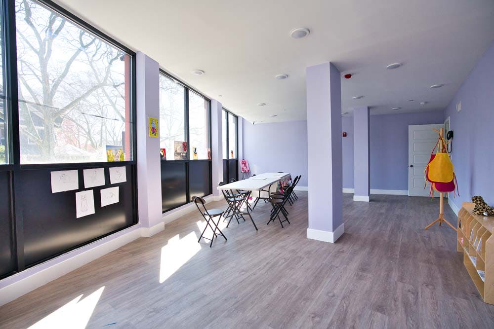 Empty room with large windows, long table, and folding chairs