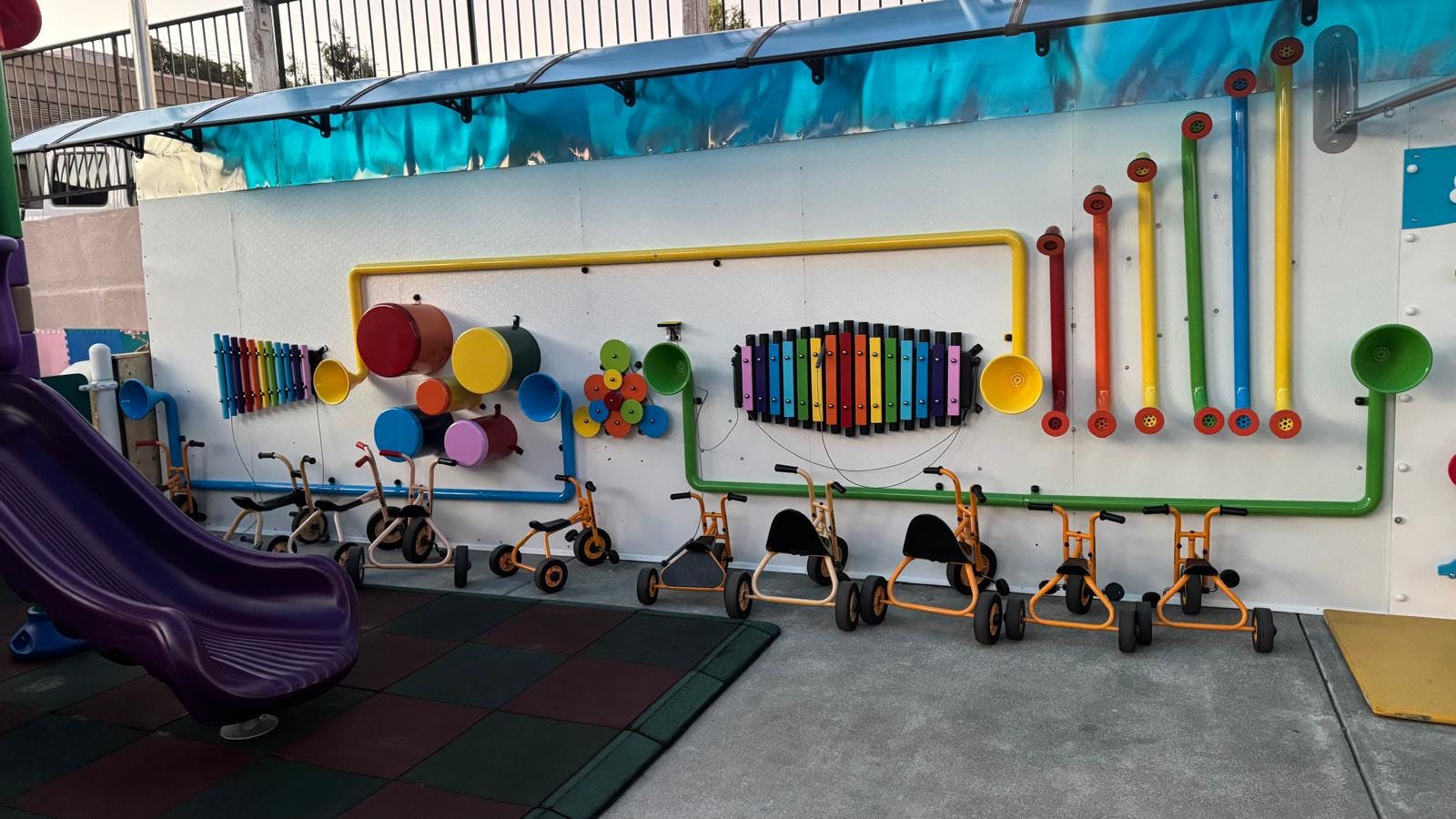 Outdoor musical sensory wall with tricycles on a playground