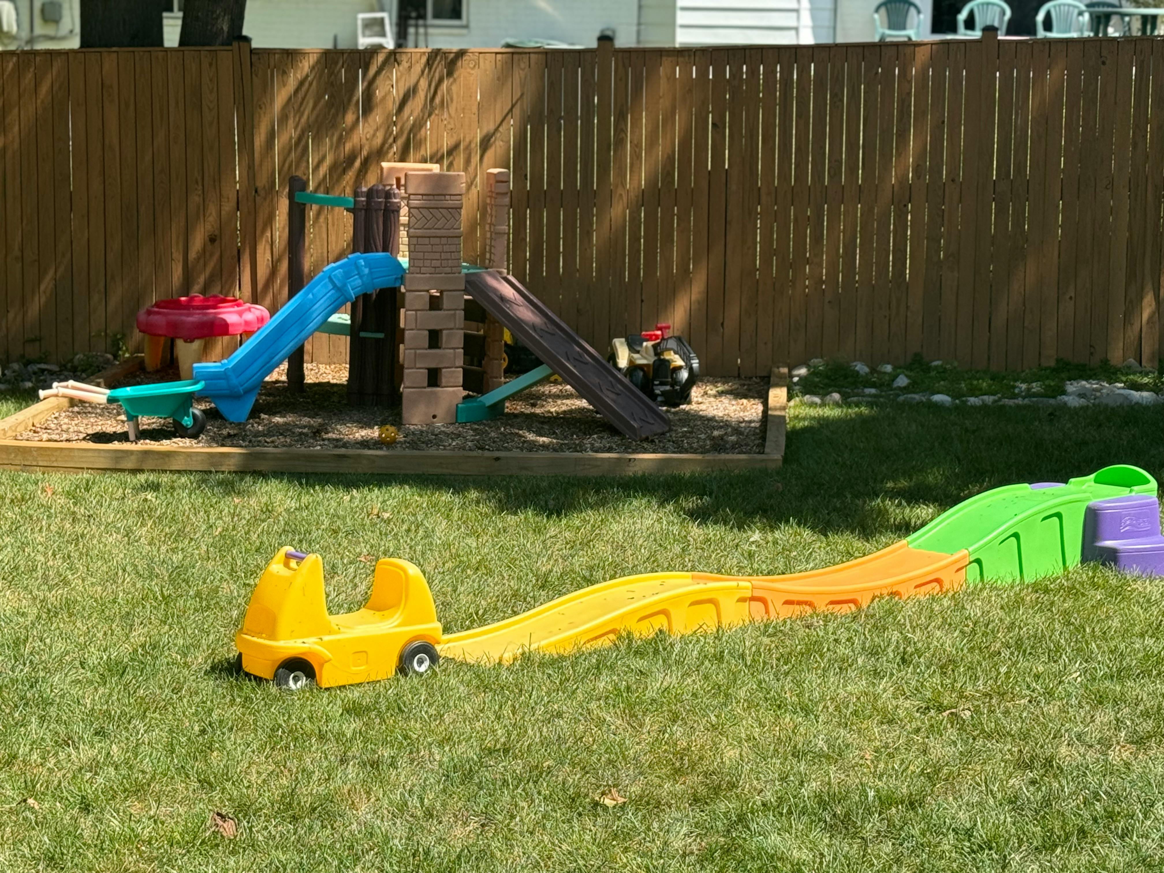 Playground with a slide and a small roller coaster toy on grass