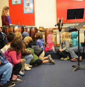 Adult playing drums for children sitting on the floor
