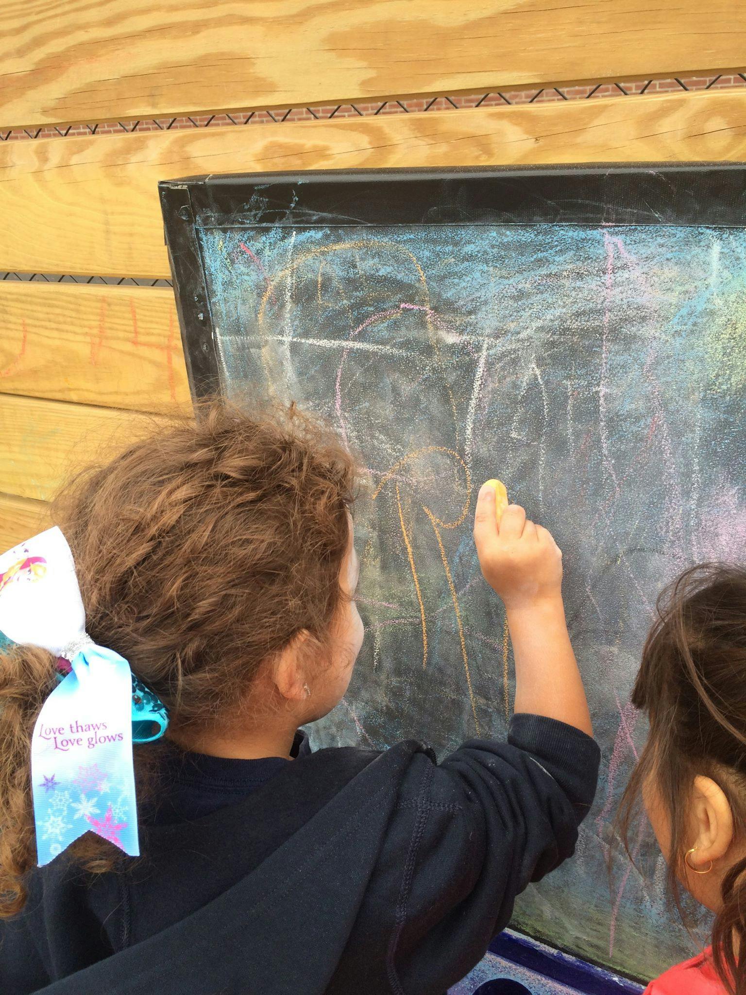 Child drawing on a chalkboard with chalk