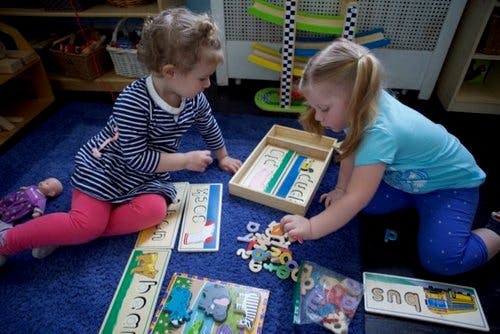 Two children playing with educational toys on a blue rug