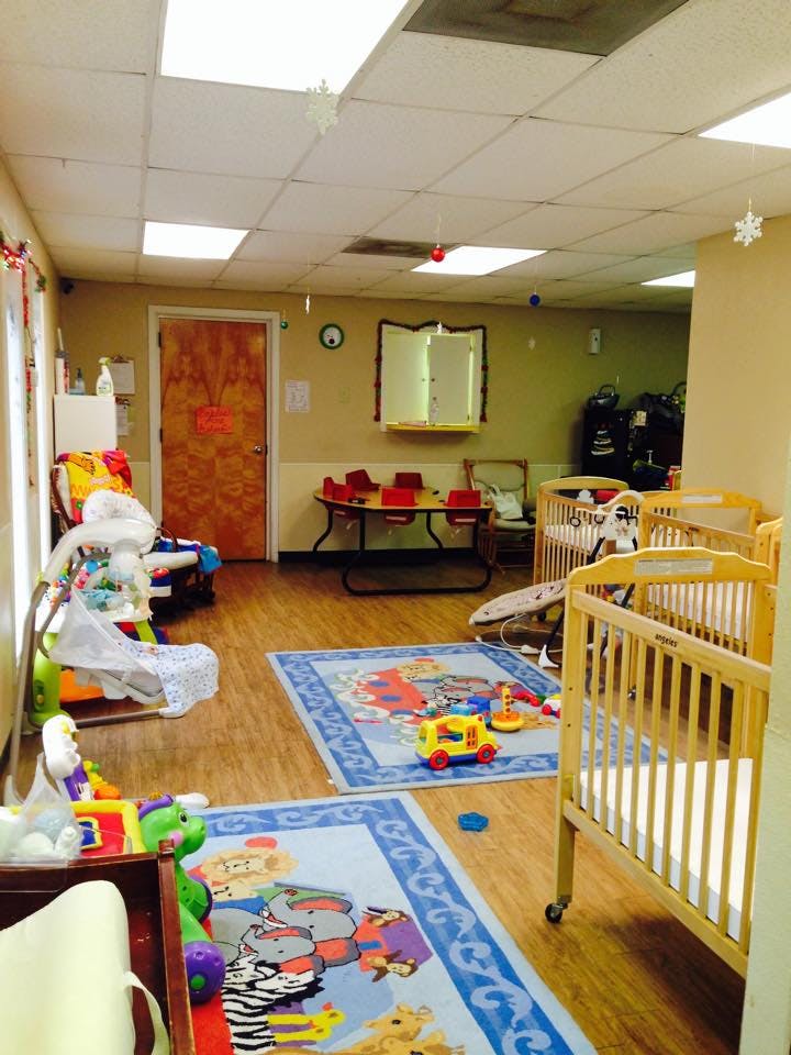 Daycare room with cribs, play mats, and small table with chairs