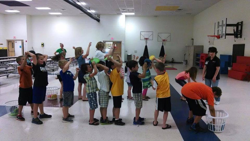Children playing a game with baskets and balls in a large room