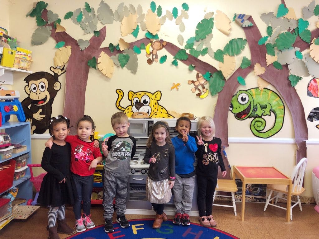 Group of children standing in a classroom with animal cutouts on the wall