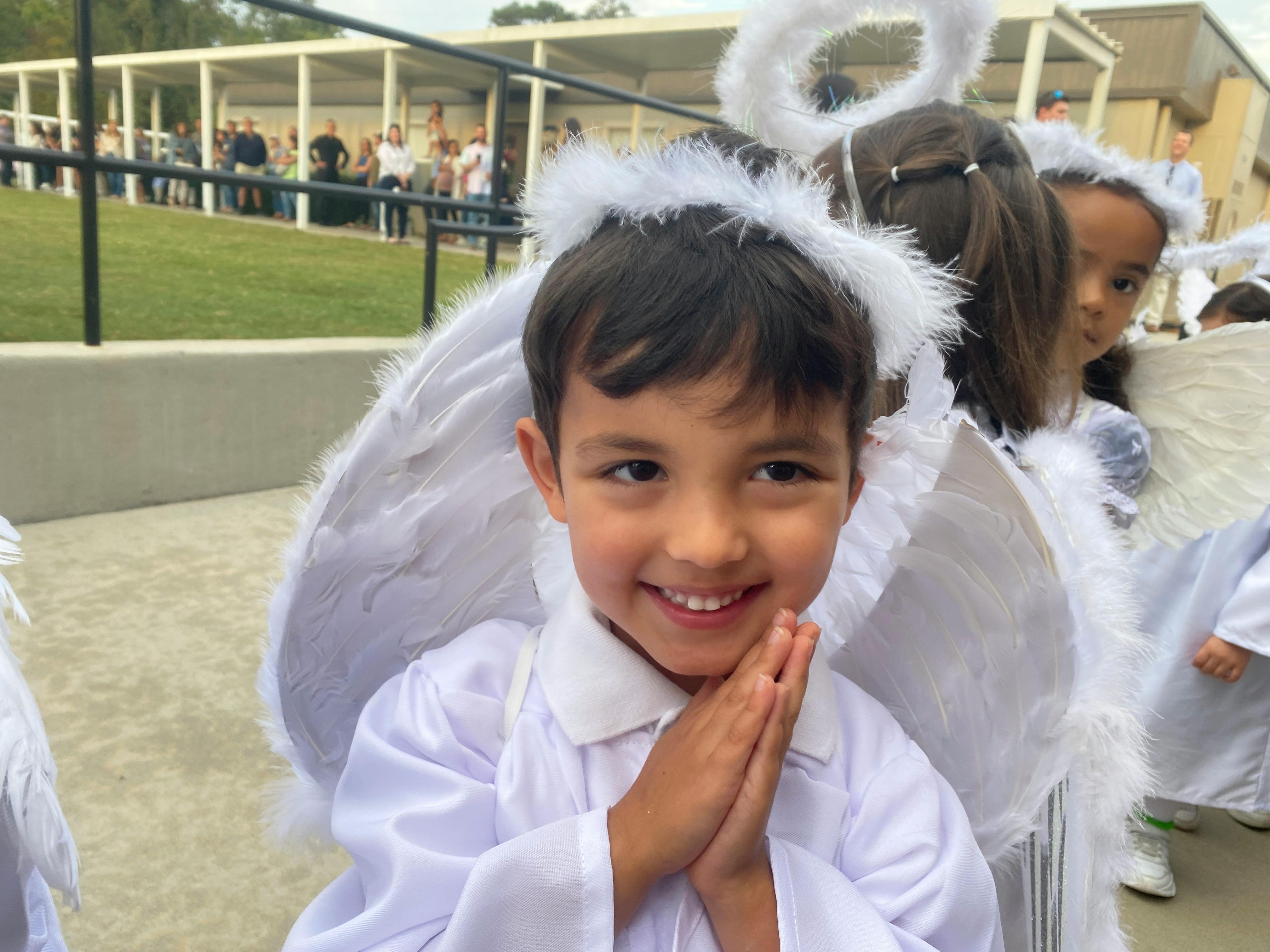 Child in white angel costume with hands clasped