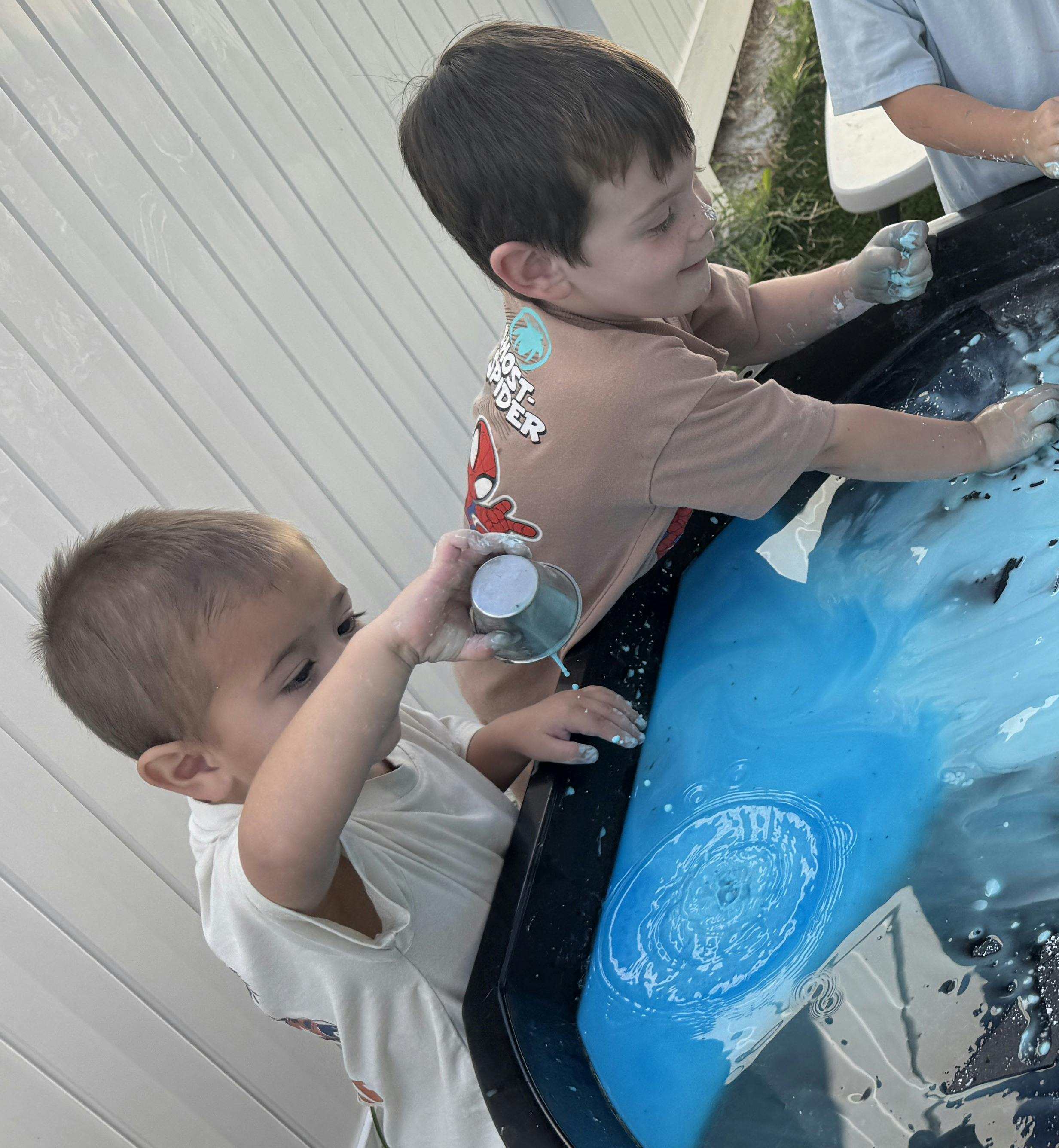 Two children playing with blue paint