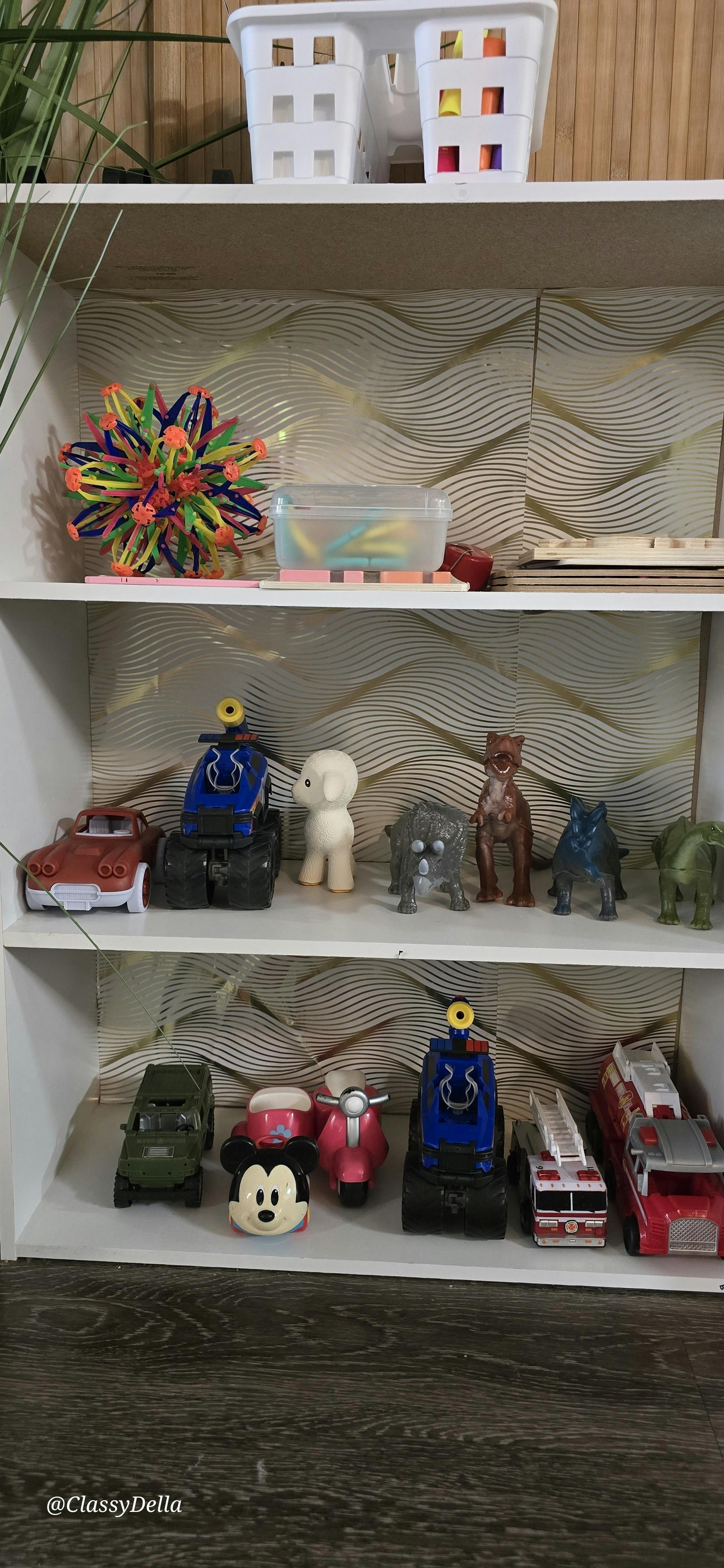 A shelf displaying toy cars, animal figures, and a small vehicle