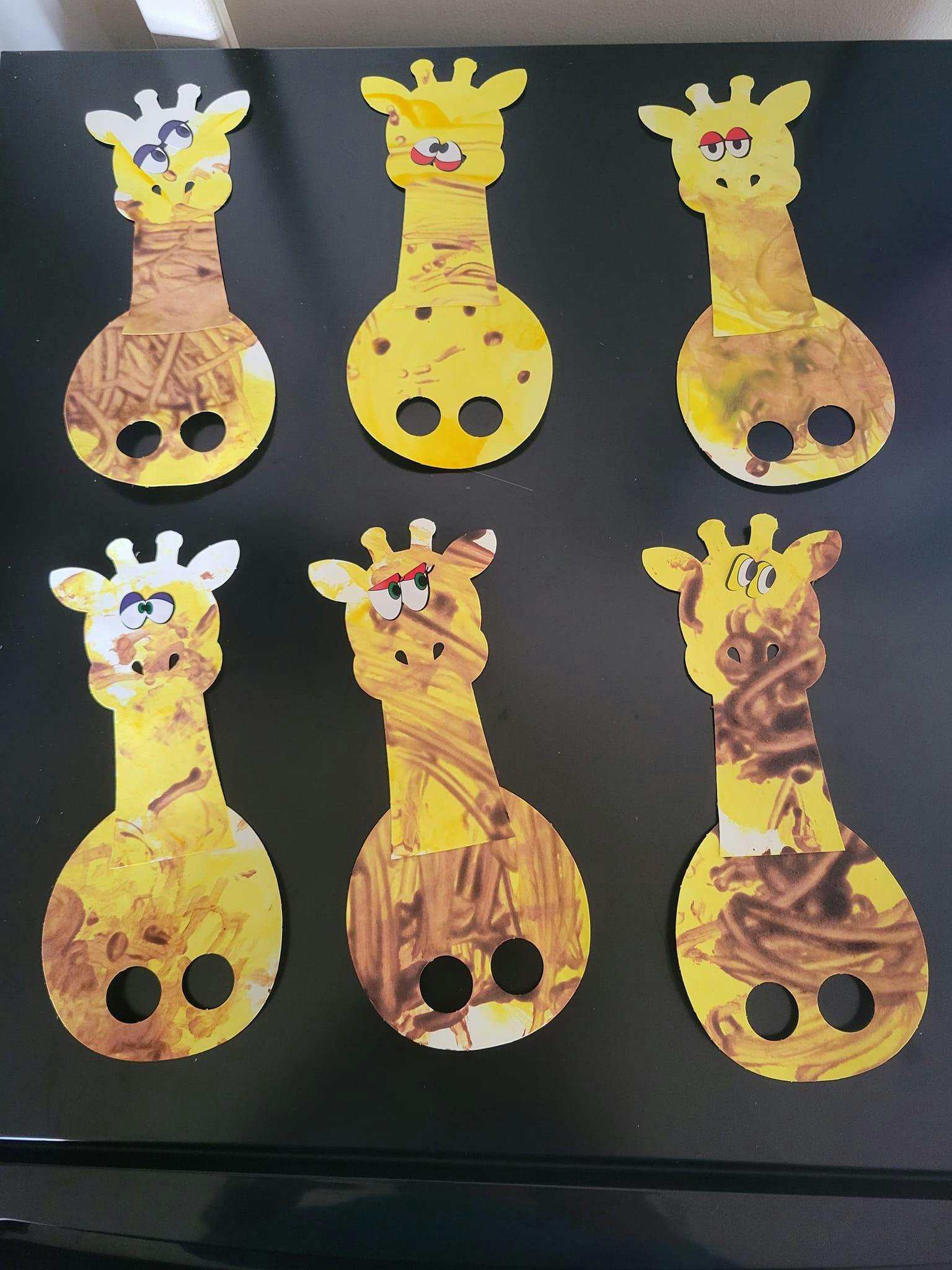 Six giraffe-shaped paper cutouts with painted bodies
