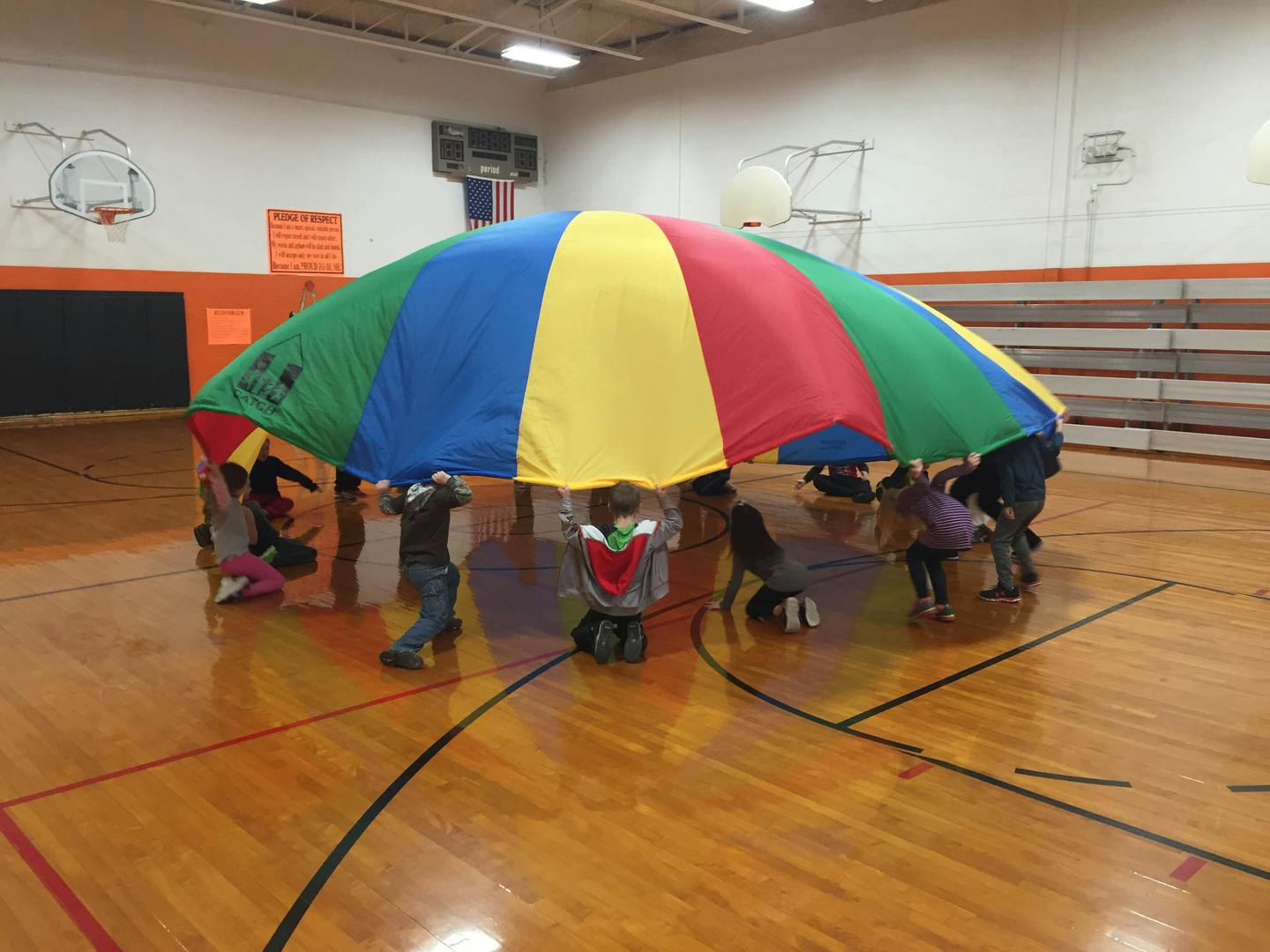 Children playing with a colorful parachute in a gymnasium